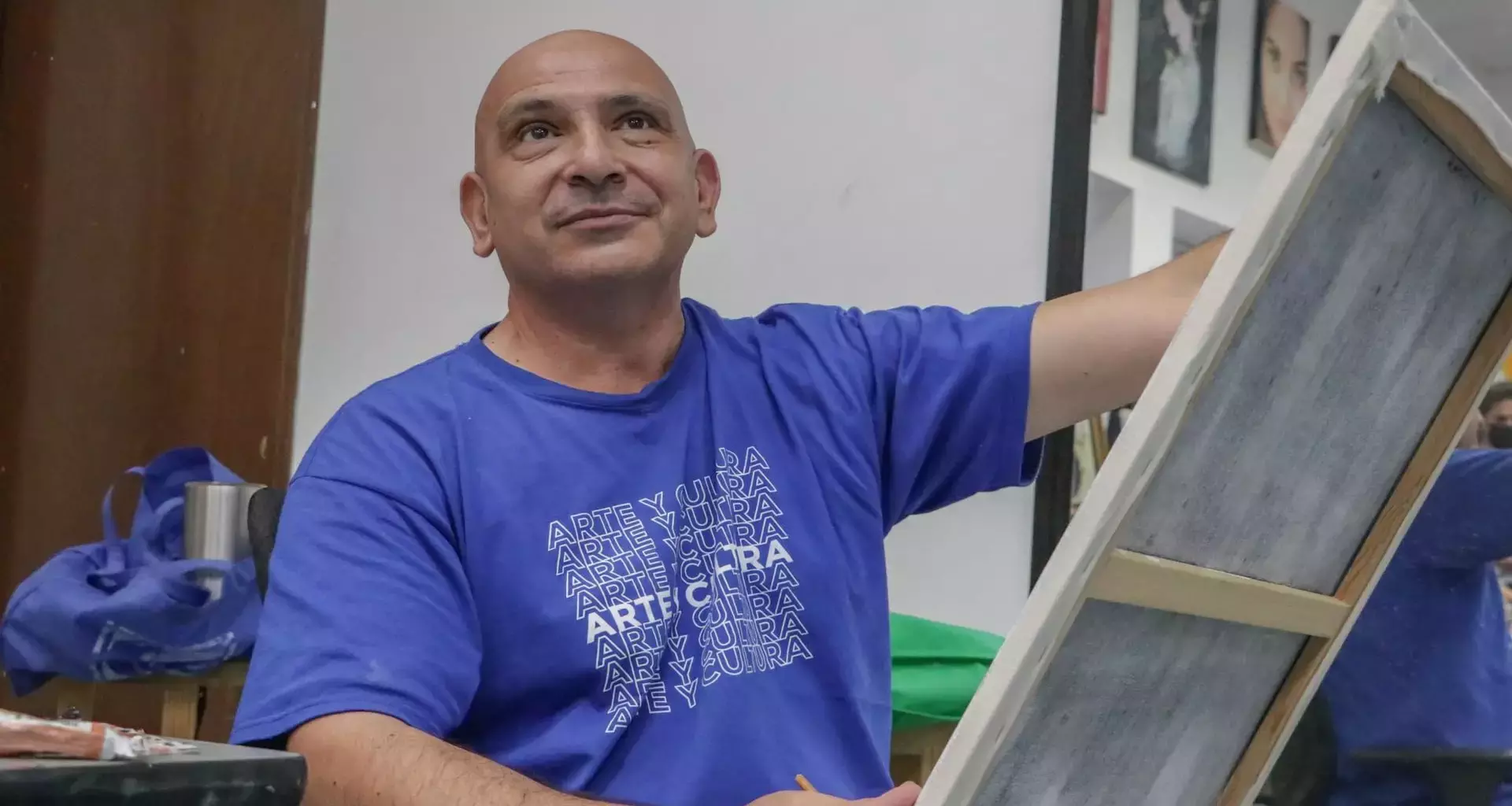 Profesor de artes plásticas pintando un cuadro con ligera sonrisa volteando hacia arriba.