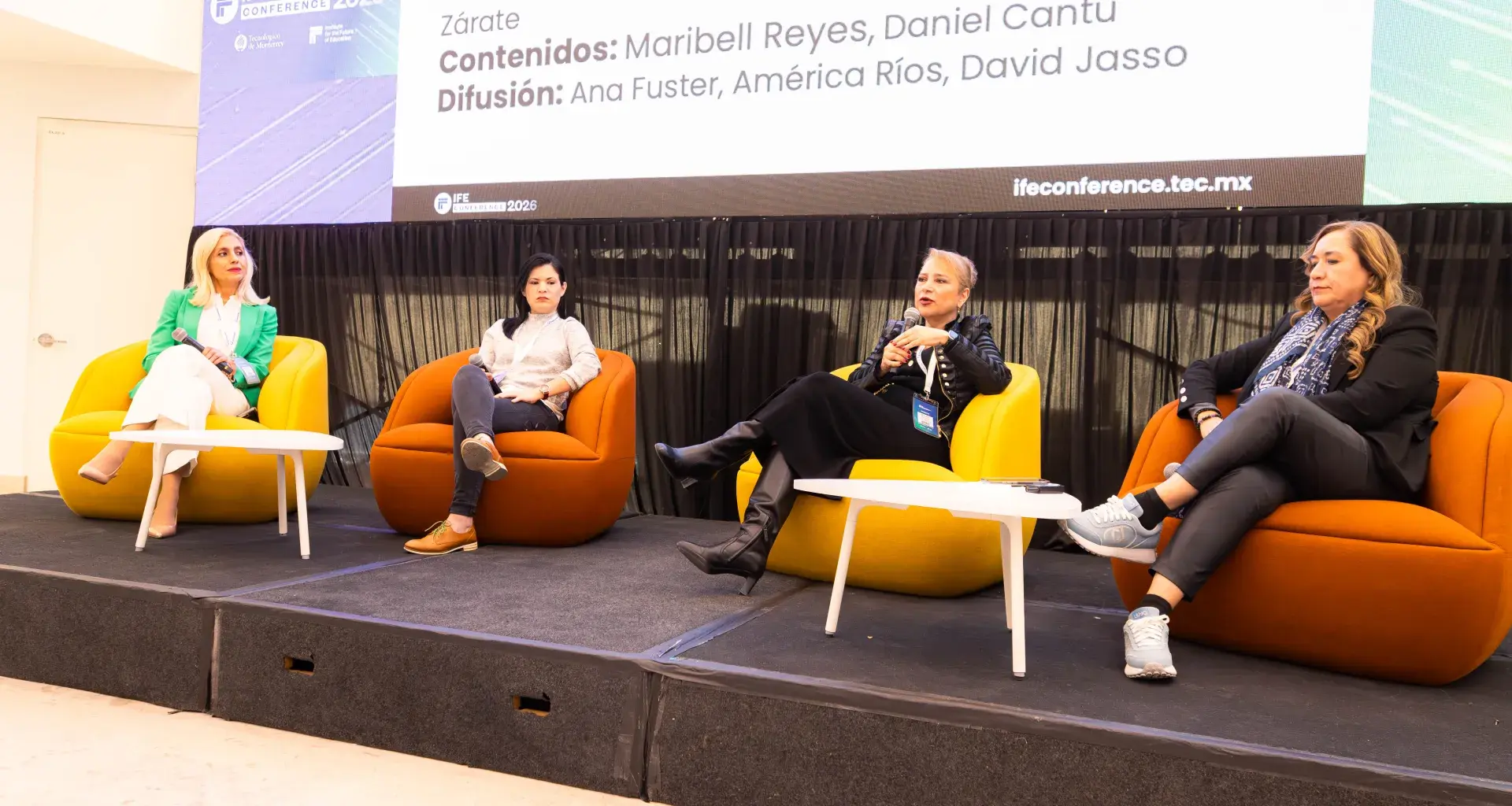 Panel de discusión durante la presentación de InnovaTED, donde cuatro mujeres participan sentadas en sillones de colores sobre un escenario, dialogando sobre innovación y transformación educativa frente a una audiencia. Detrás de ellas se observa una pantalla.