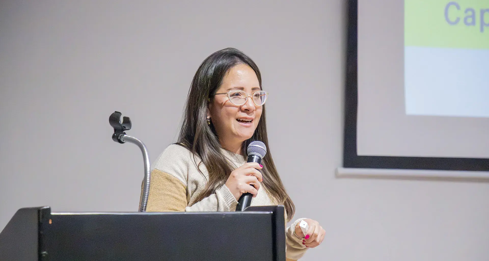 Directora del programa de Licenciatura en Contaduría Pública y Finanzas sostiene micrófono durante conferencia