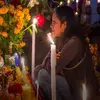 Mujer frente a ofrenda del Día de Muertos