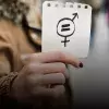 Mujer sosteniendo una hoja con signo de igualdad de género