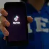 Persona enseñando su celular con la pantalla de inicio de la aplicación de TikTok.