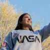 Carolina señalando el cielo con una sudadera de la nasa