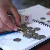 Persona cuenta dinero en escritorio con libreta y tarjetas bancarias