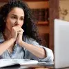 Mujer frente a laptop, con manos en la boca, signo de preocupación