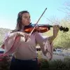 Mariana Páez tocando la viola frente a una vista de la Cápsula del Tiempo del campus Sonora Norte