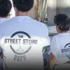 Vista de espaldas de tres voluntarios portando camisetas blancas con un logo que dice Street Store 2025