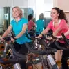 Mujeres de distintas edades realizando spinning en un gimnasio