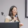 Directora del programa de Licenciatura en Contaduría Pública y Finanzas sostiene micrófono durante conferencia