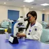 Karla Rojas observa una muestra a través de un microscopio en un laboratorio académico.