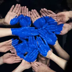 Manos juntas con pintura azul formando un corazón