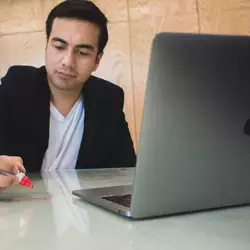 Jóven escribiendo en una mesa de vidrio