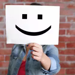 Mujer mostrando una hoja de papel con una carita feliz