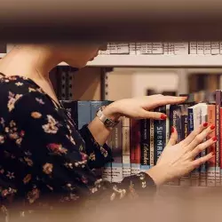 mujer en biblioteca buscando libros