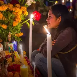 Mujer frente a ofrenda del Día de Muertos