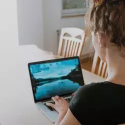 Mujer frente a su computadora esperando conectarse a entrevista.