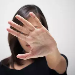 Mujer con palma de la mano abierta, en señal de poner un alto a la violencia de género