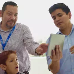 alumno del Tec presentando su proyecto de ingeniería a niños y a un profesor.