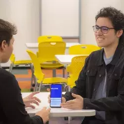 alumno muestra su app de lenguaje de señas en su teléfono