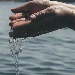 Manos agarrando agua y dejándola caer. 