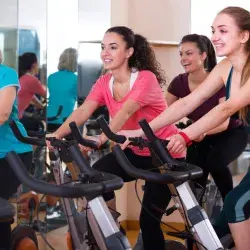Mujeres de distintas edades realizando spinning en un gimnasio