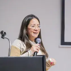 Directora del programa de Licenciatura en Contaduría Pública y Finanzas sostiene micrófono durante conferencia