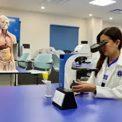 Karla Rojas observa una muestra a través de un microscopio en un laboratorio académico.