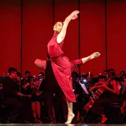 Bailarina en rojo del Tec de Monterrey campus Laguna realiza su movimiento dancístico con la Orquesta filarmónica DIME de fondo en el Teatro Nazas Torreón