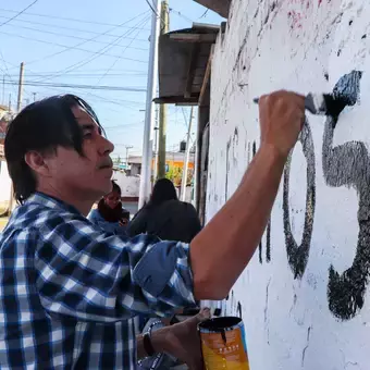 Alumnos y Armando Alanís pintando paredes con frases poéticas