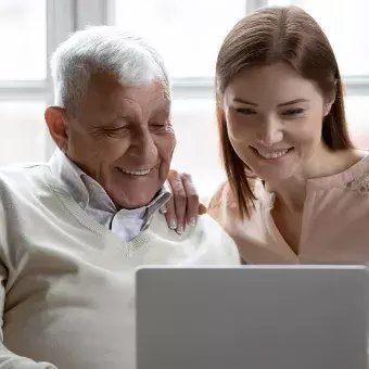 Adulto mayor y mujer joven usando una laptop