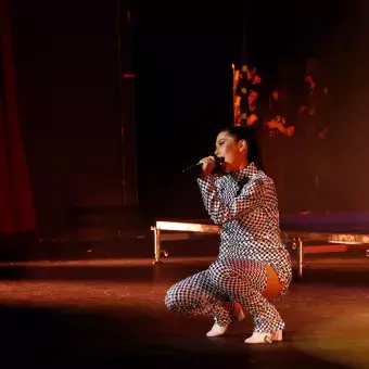 Cantante hincada cantando en el escenario