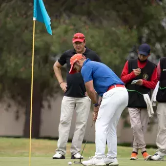 Grupo de jugadores viendo a golfista intentar el putt