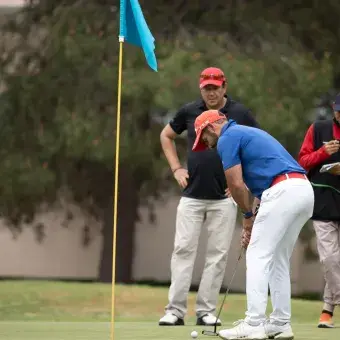 Grupo de jugadores viendo a golfista intentar el putt