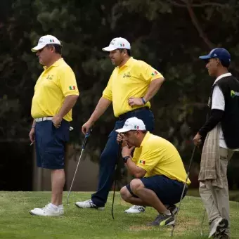 Jugadores, uno incado, viendo a otros golfistas