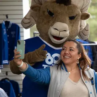 Mujer tomándose foto con Teus, la mascota del Tec