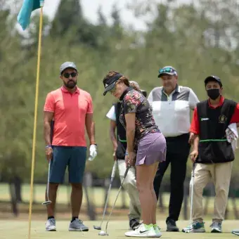 Grupo de golfistas viendo a una jugadora intentar un putt