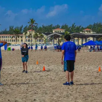 Alumnos jugando voleibol en la playa
