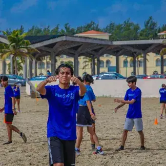 Alumno saludando a la cámara en la playa miramar