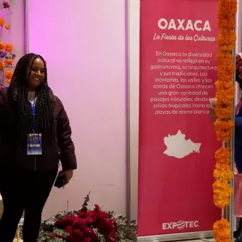 Mujer se fotografía frente a stand de Oaxaca.