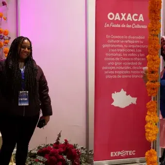 Mujer se fotografía frente a stand de Oaxaca.