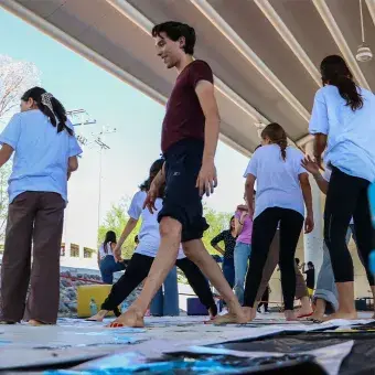 Grupo de alumnos caminando sobre una lona descalzos con los pies cubiertos de pintura.