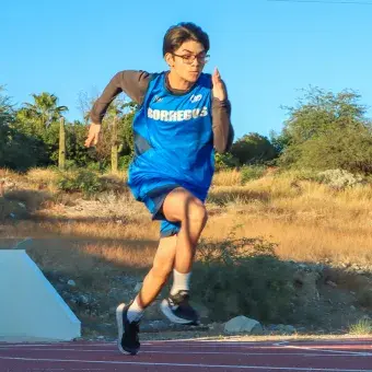 Joven deportista corriendo en una pista de atletismo. 