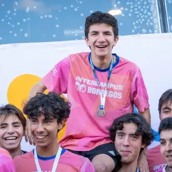Jugadores de fútbol sostienen a un compañero en sus hombros, todos portan medallas en sus cuellos. 