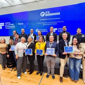 Grupo de docentes y directivos del Tecnológico de Monterrey posan con sus reconocimientos NOVUS durante la ceremonia de entrega a los mejores proyectos de innovación educativa generación 2023, en el marco de IFE Conference, frente a una pantalla institucional.