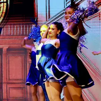 Estudiantes de la Compañía de Teatro Enrique Hernández Soto ejecutando danza en Harvard con iluminación dramática durante la puesta en escena.