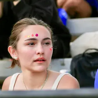 Estudiantes miran con expectación un juego de futbol desde las tribunas.