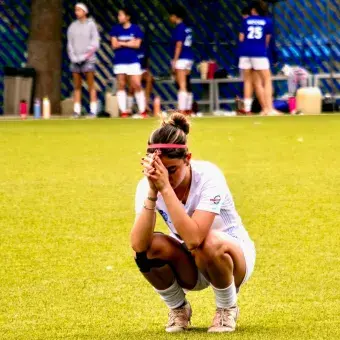 Futbolista de Borregos medita solitaria en cuclillas tras un juego.