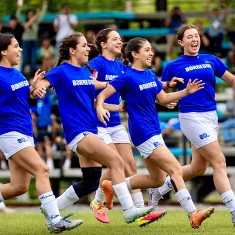 Equipo de futbol femenil corriendo unido por el campo celebrando su pase a la final..