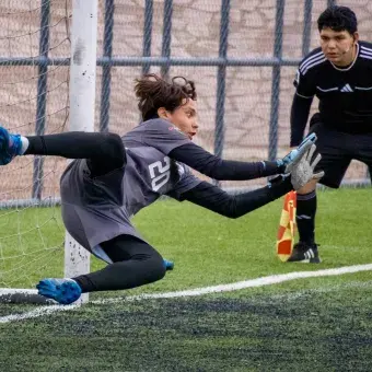 Portero volando de forma horizontal para desviar un balón que iba directo al ángulo inferior de la portería.