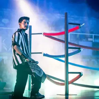 Estudiante ingresa al escenario inspirado en la lucha libre durante "Los Sonidos del Ring" en Arena Borregos